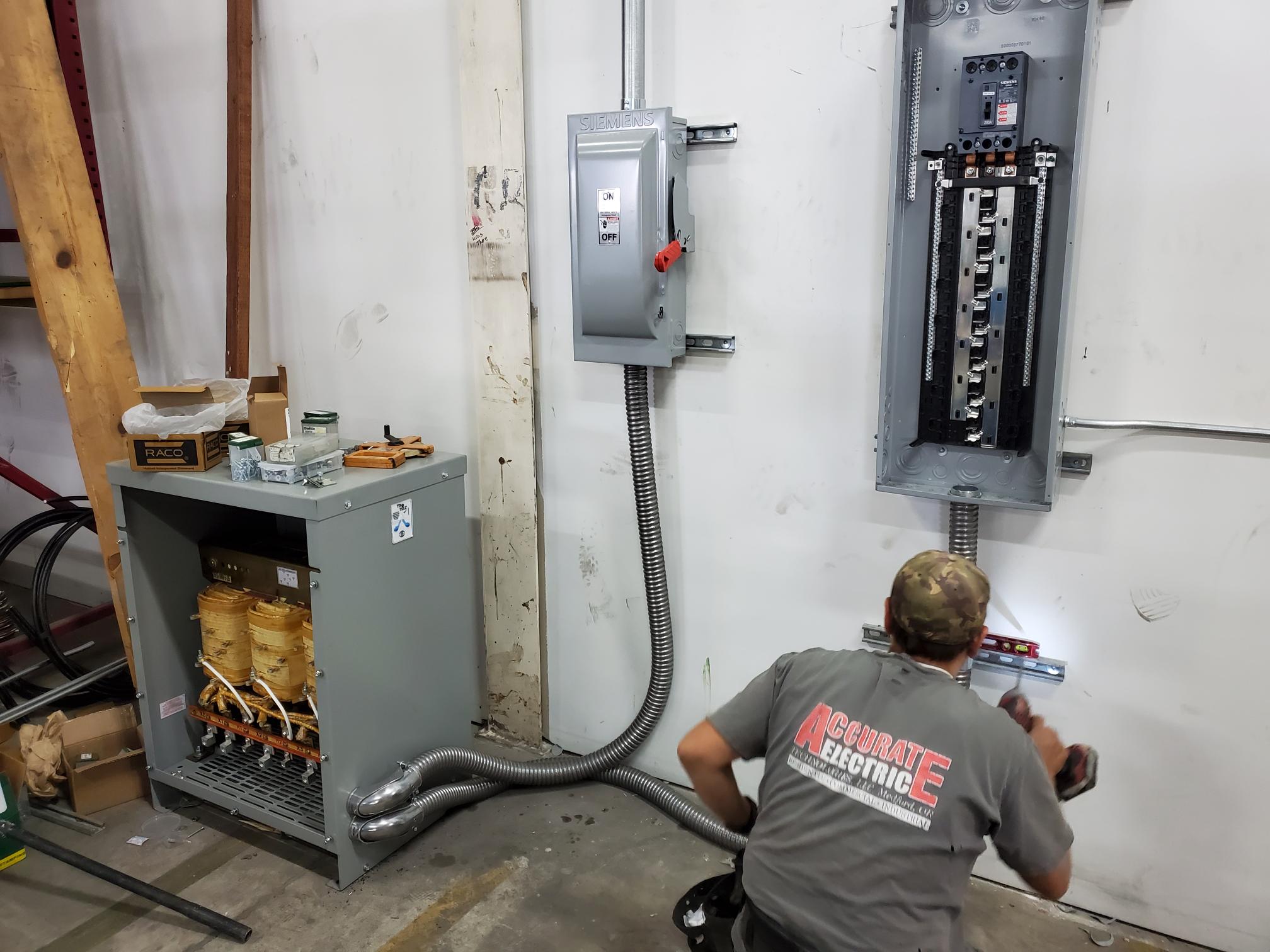 Accurate Electric electrician working beside commercial electrical equipment