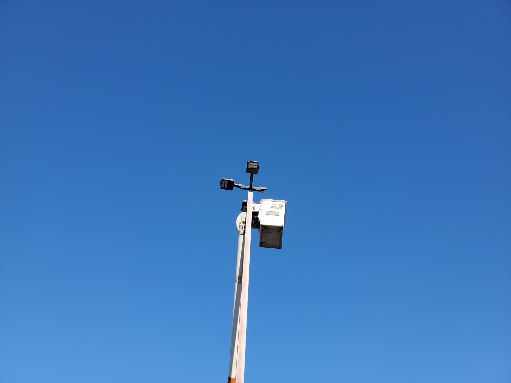 Pole-mounted exterior area lighting equipment against a blue sky