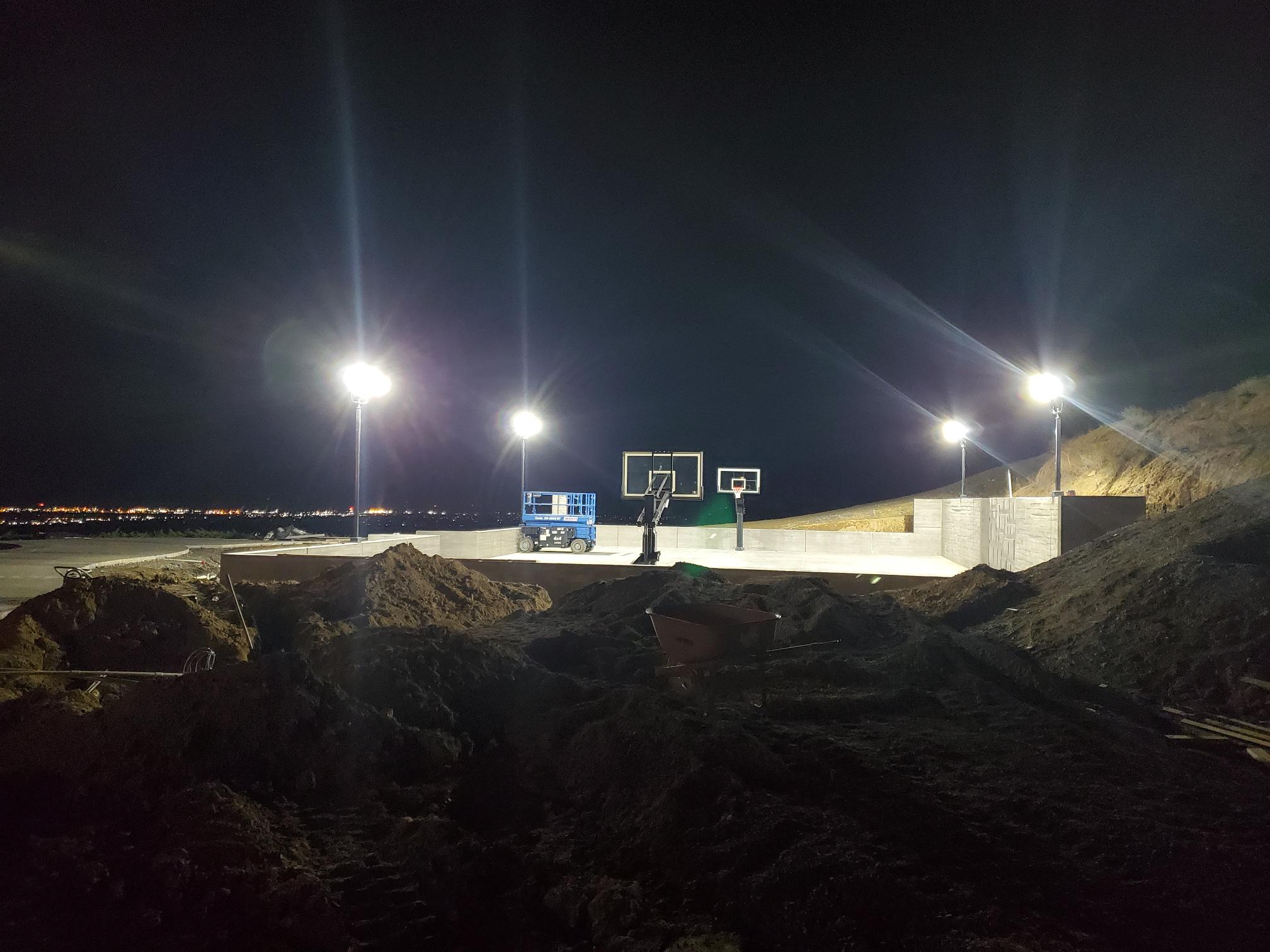 Outdoor basketball court illuminated by site lighting at night